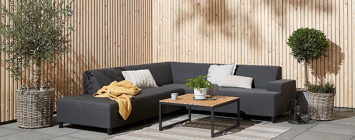 Graues Lounge-Sofa in der Ecke einer Terrasse