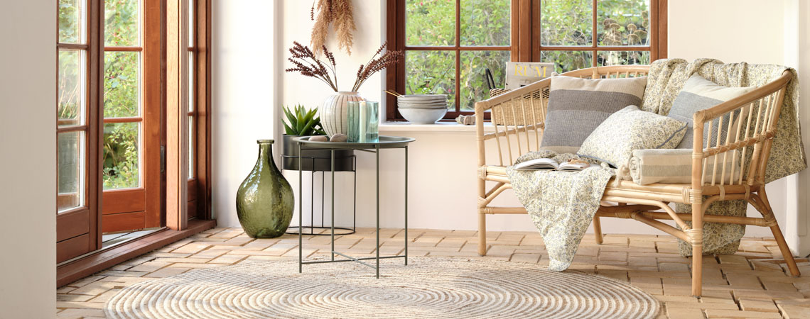 Grüne Bodenvase, schwarzer Beistelltisch und Sofa mit Steppdecke und Blumenkissen
