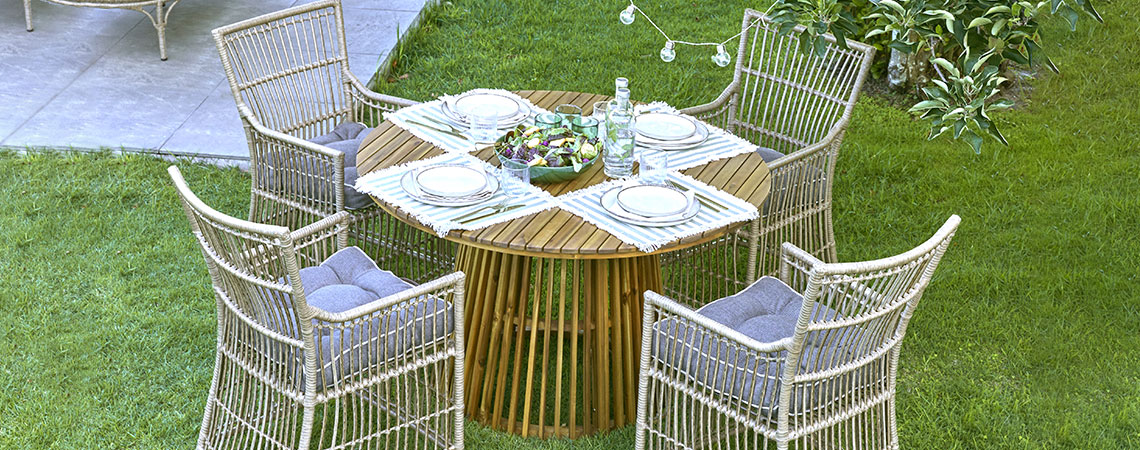 Ein runder Gartentisch und vier Gartenstühle auf einer Rasenfläche
