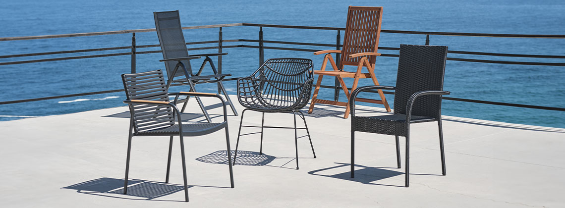 Fünf unterschiedliche Gartenstühle auf einer Terrasse mit Meerblick