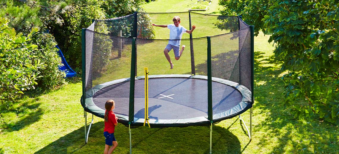 Kinder spielen auf einem großen Trampolin im Garten 