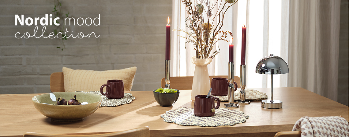 Esstisch mit Schalen, Tassen, Tischsets, Vase, Kerzenhaltern und batteriebetriebener Lampe