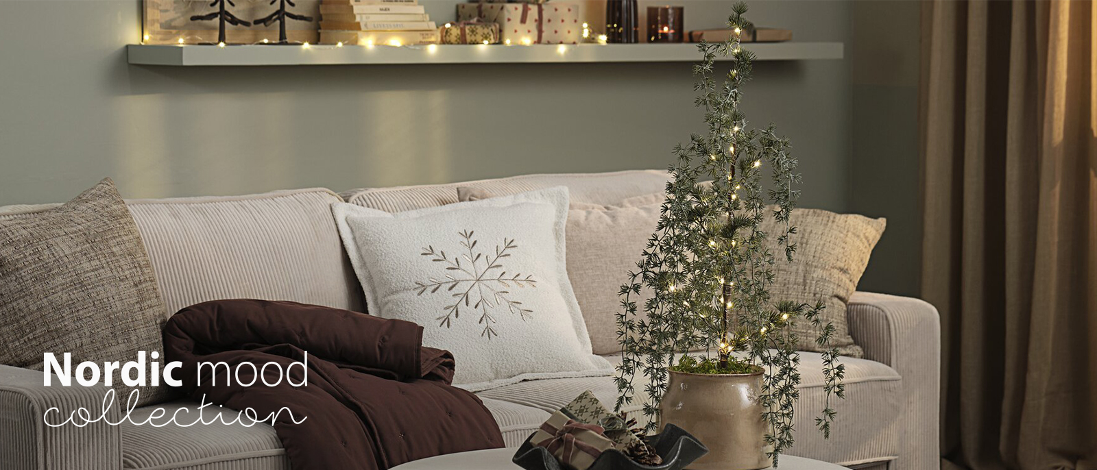 Sofa mit Kissen und Plaids in einem weihnachtlich dekorierten Wohnzimmer