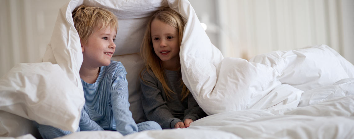 Zwei Kinder unter einer Bettdecke