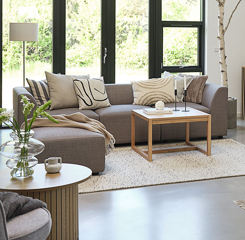 Minimalistischer Couchtisch aus Eiche in einem hellen Wohnzimmer mit großem Sofa und dekorativen Kissen