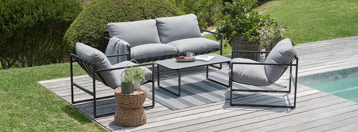 Gartenlounge-Set mit Loungesofa, Lounge-Sesseln und Tisch in einem Garten neben einem Pool