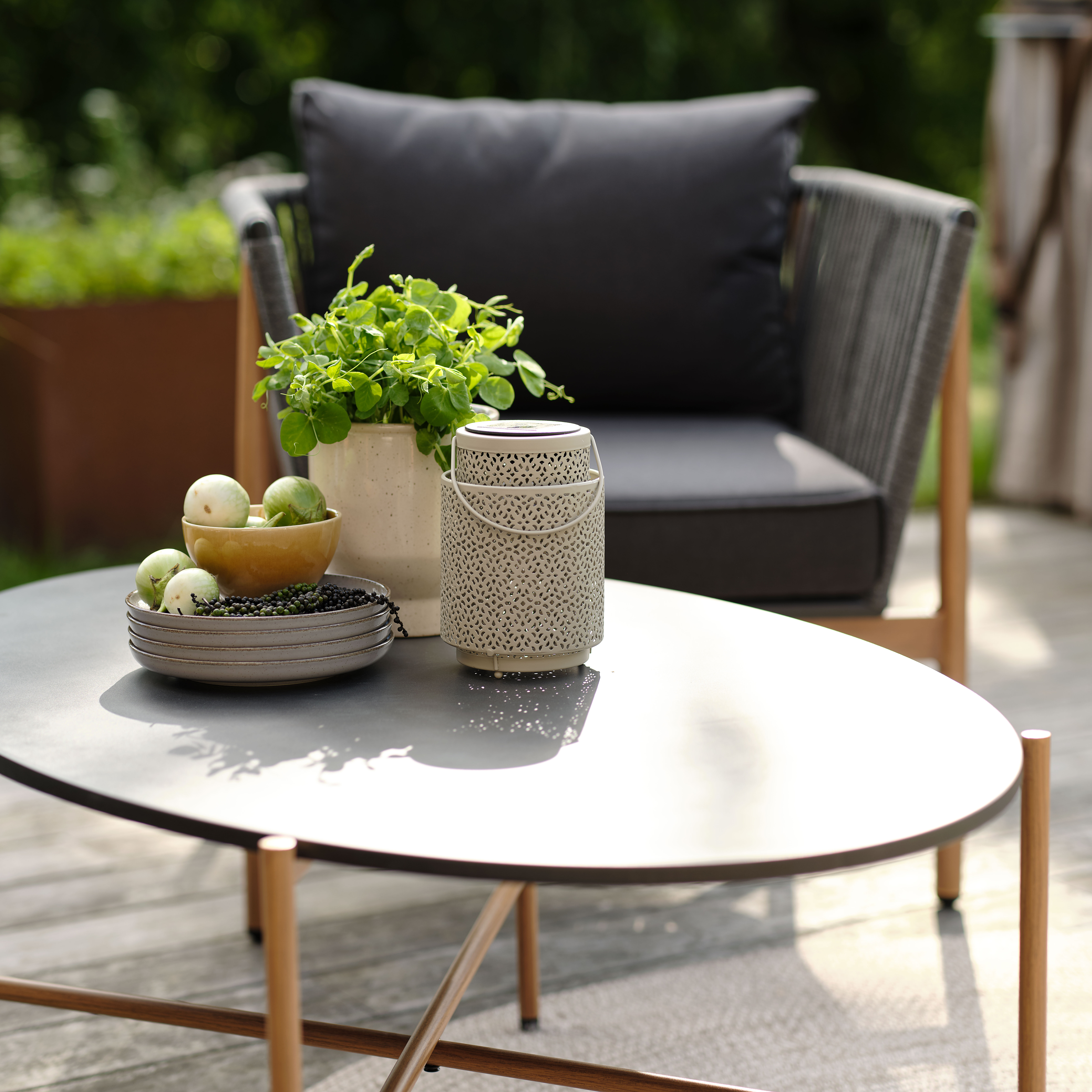 Loungetisch mit Laterne und Pflanzgefäß auf einer Terrasse