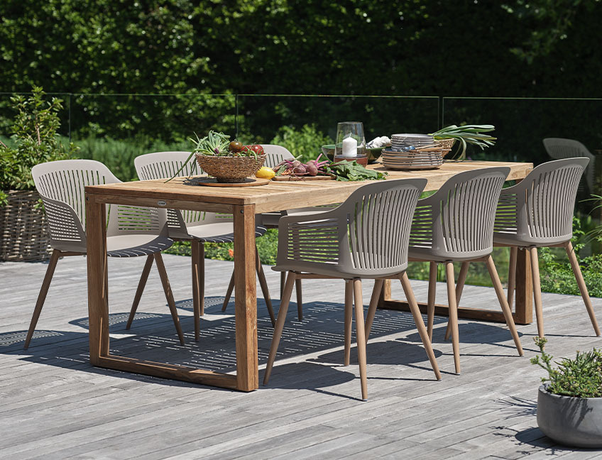 Auf der Terrasse im Garten stehen ein Gartentisch aus Hartholz und passende Gartenstühle