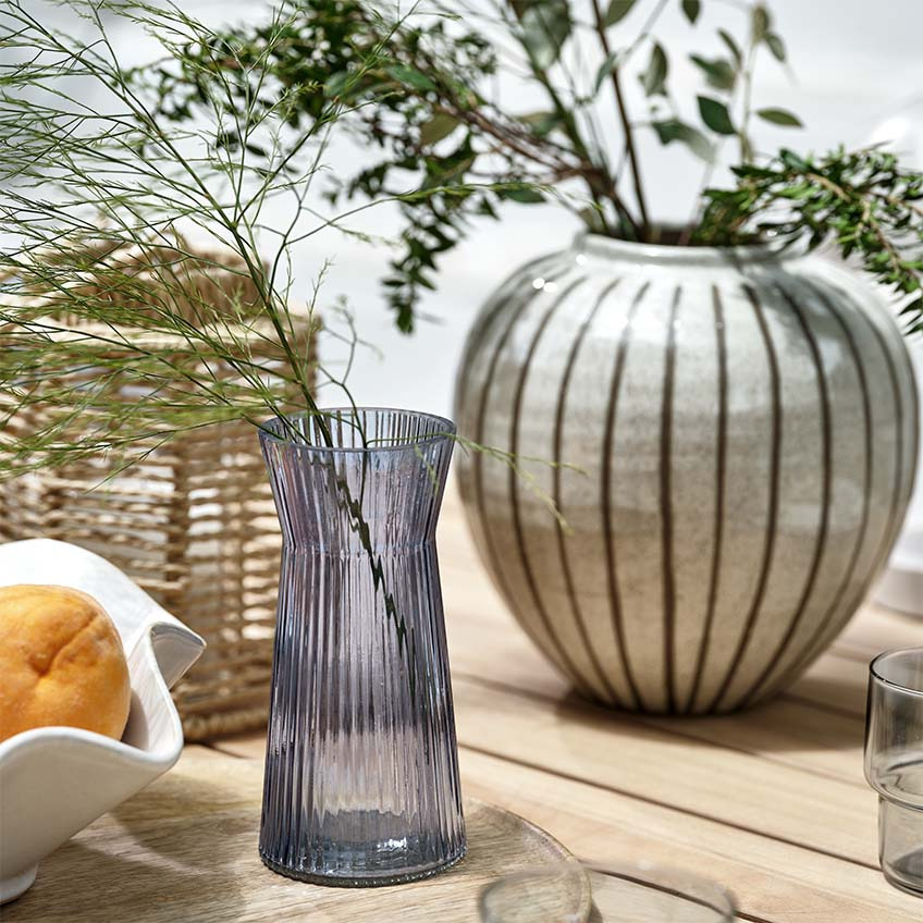 Vasen, Laterne und Schale auf Gartentisch im Freien
