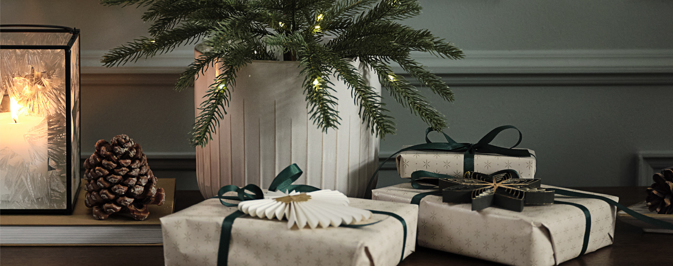 Weihnachtsgeschenke auf einem Sideboard mit einem künstlichen Baum