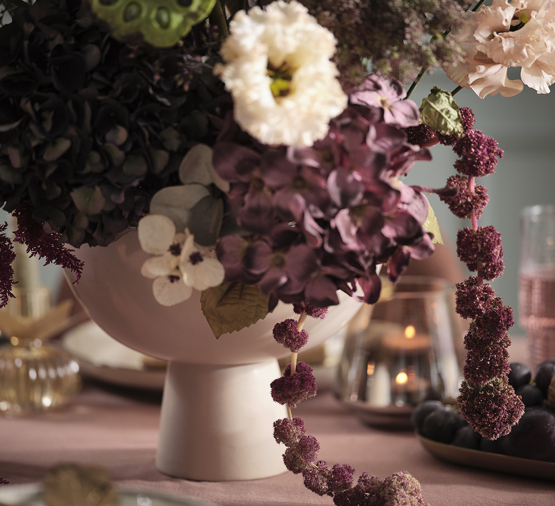 Schale mit künstlichen Blumen auf einem festlich gedeckten Esszimmertisch