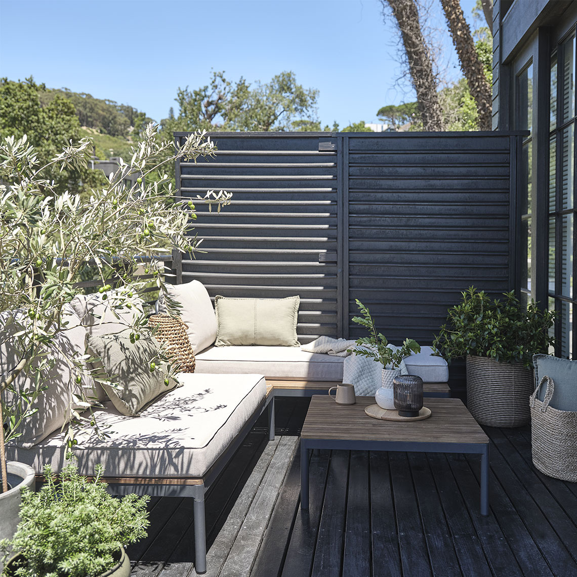 Gartenlounge auf einer kleinen Terrasse mit Pflanzen und Pflanzgefäßen
