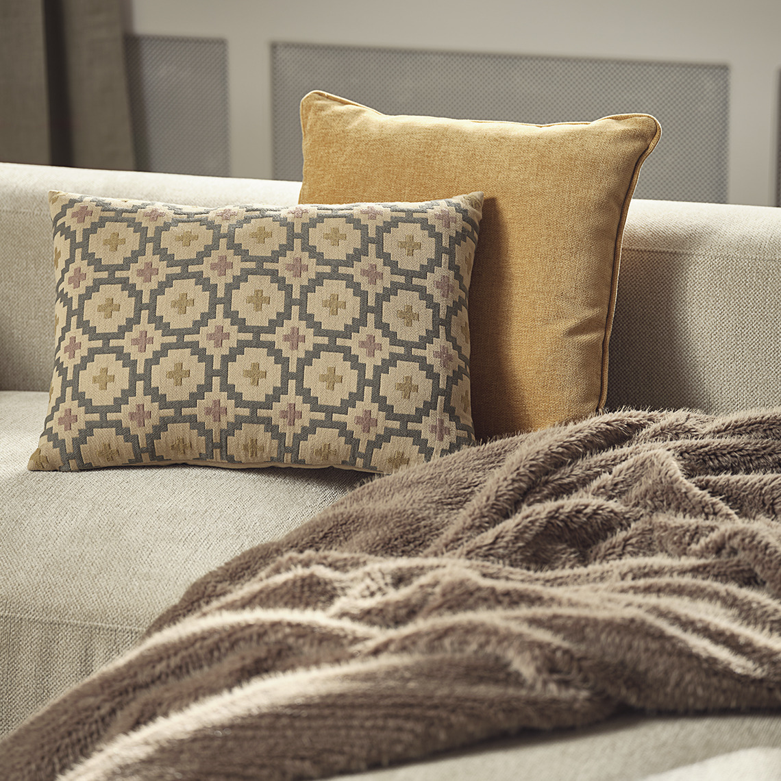 Gelbe HORNFIOL- und gemusterte BANKSIA-Kissen, VINTEREIK-Decke aus Kunstfell Sofa mit gelben und gemusterten Kissen und einer Decke