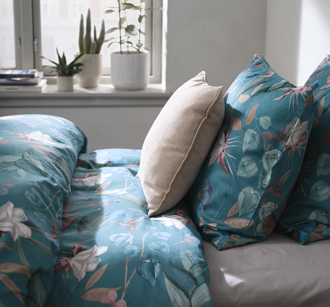 Kombiniere BERTHA mit kontrastierenden monochromen Artikeln für einen dynamischen Look Schlafzimmer mit geblümter Bettwäsche und zusätzlichem Kissen in Kontrastfarbe
