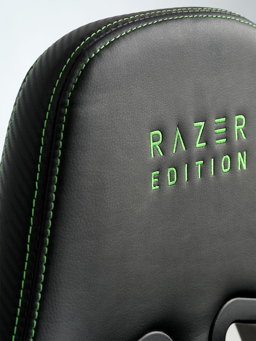 Nahaufnahme eines schwarzen Razer Gaming-Stuhls mit grünen Nähten und der Stickerei „RAZER EDITION“ auf der Rückenlehne