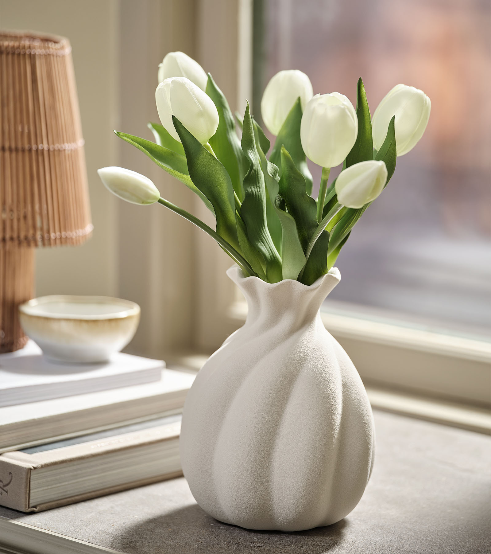 Künstlicher Blumenstrauß (Nachbildung weißer Tulpen) mit grünen Blättern in einer weißen Vase