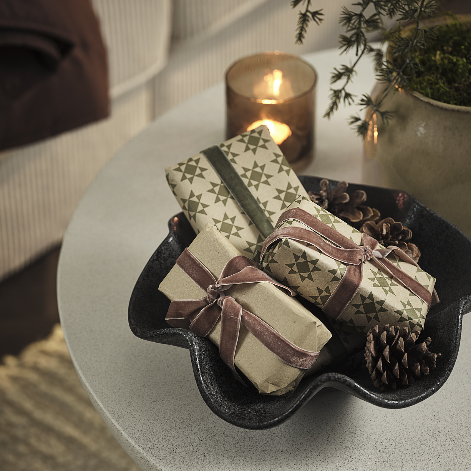 Schale mit Weihnachtsgeschenken und Tannenzapfen