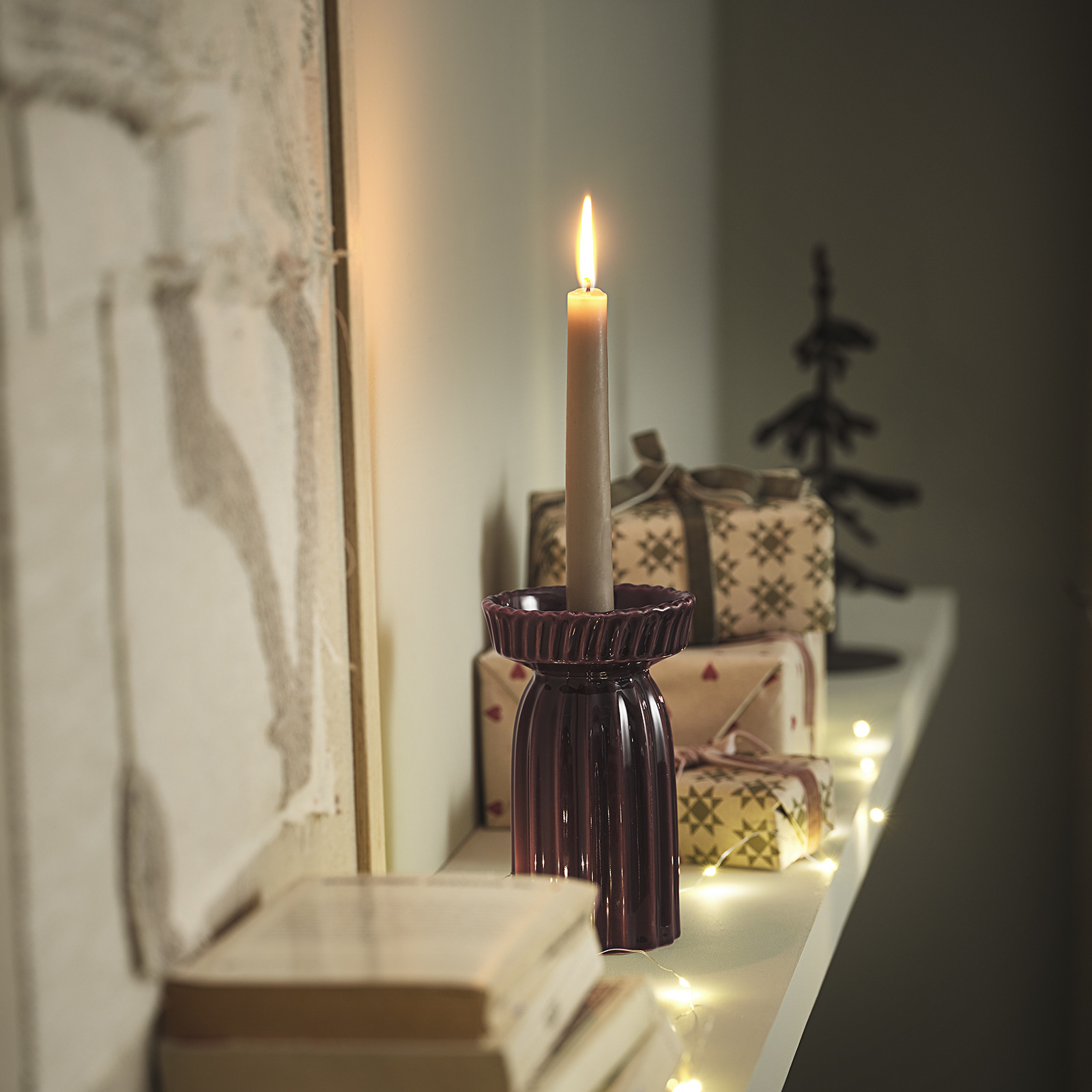 Kerzenständer mit brennender Kerze auf einem Regal