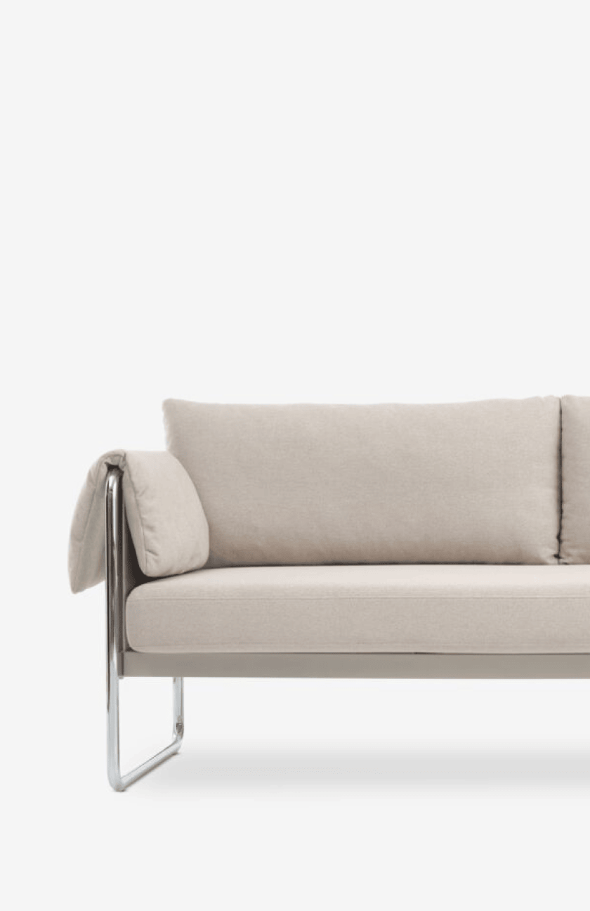 Classic sofas Close-up of a beige sofa with chrome tubular legs and a bolster-style armrest, against a plain white background.