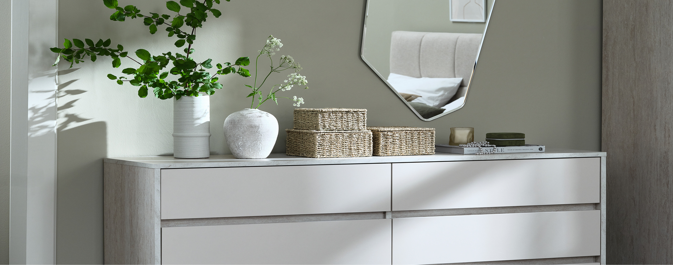 Hallway cover Hallway console table with woven storage baskets, ceramic vases with greenery, and an angular mirror reflecting a bedroom.