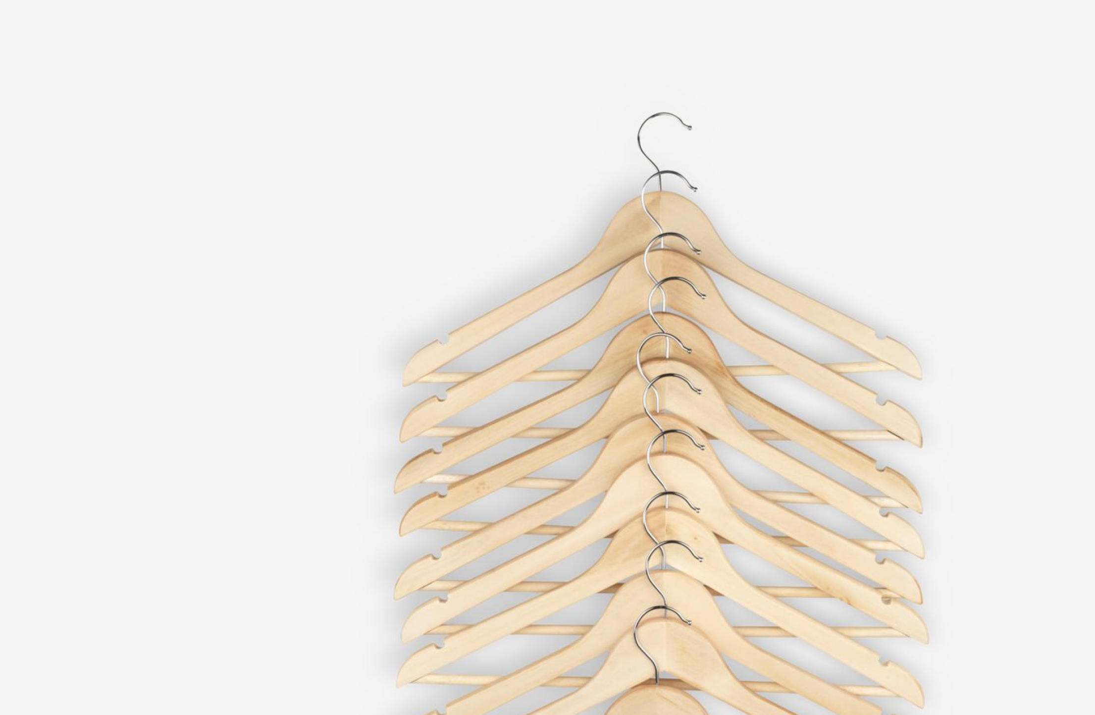 Hangers Stack of natural wood clothing hangers with chrome hooks, viewed from above.