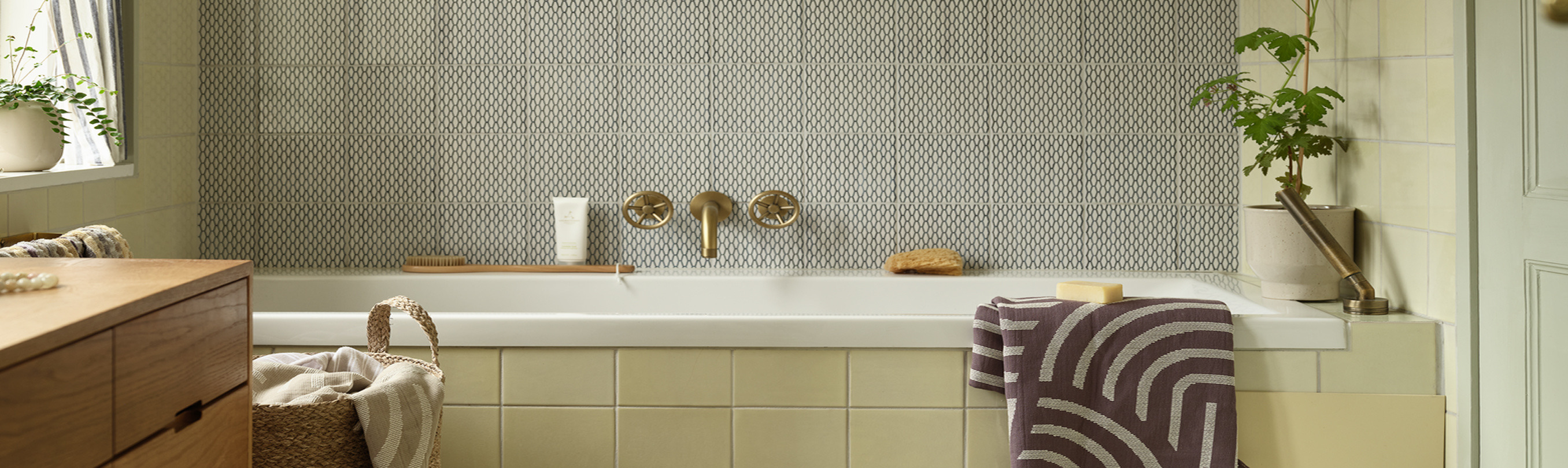 Laundry room cover Laundry room with a patterned tile accent wall, brass fixtures, a bathtub, a woven basket, and a striped towel.
