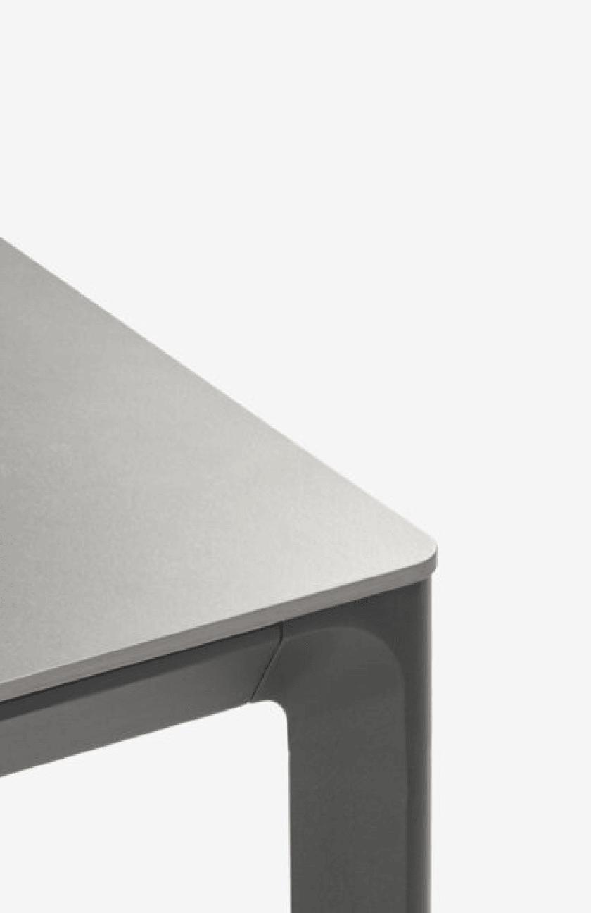 Metal tables Close-up corner of a grey stone-effect table top on a dark metal frame, shown against a plain white background.