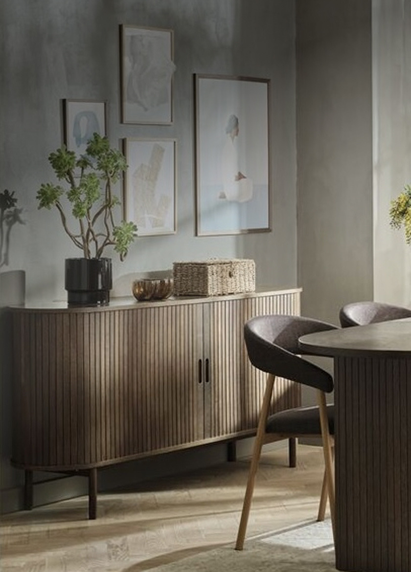 Sideboards Dark wood ribbed sideboard styled with a potted plant and a woven basket, beneath framed art in a dining area.