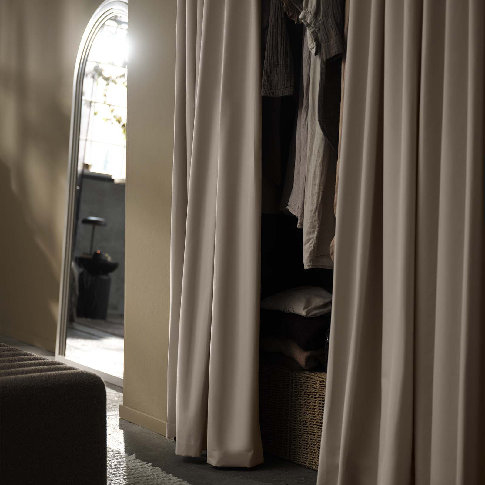 Beiger Verdunkelungsvorhang als dekorative Front eines Kleiderschranks im Schlafzimmer