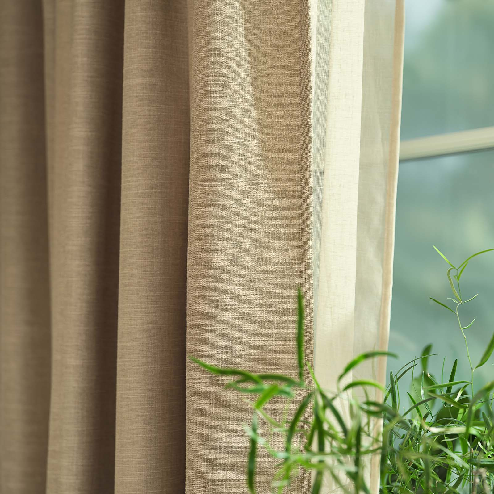Nahaufnahme eines khakifarbenen, sandfarbenen schweren Vorhangs vor einem Fenster