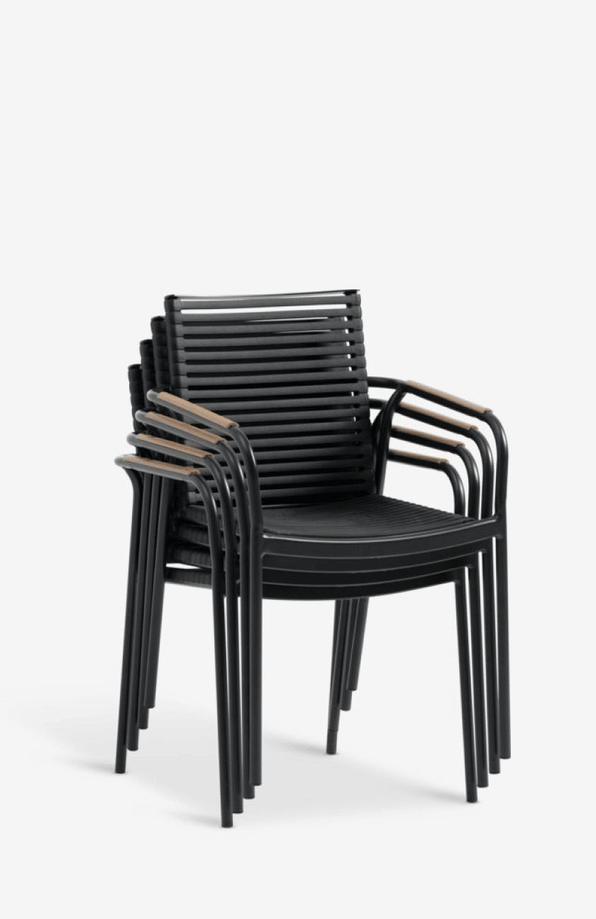 Composite chairs Stack of four black slatted composite outdoor armchairs with teak armrests, shown against a plain white background.