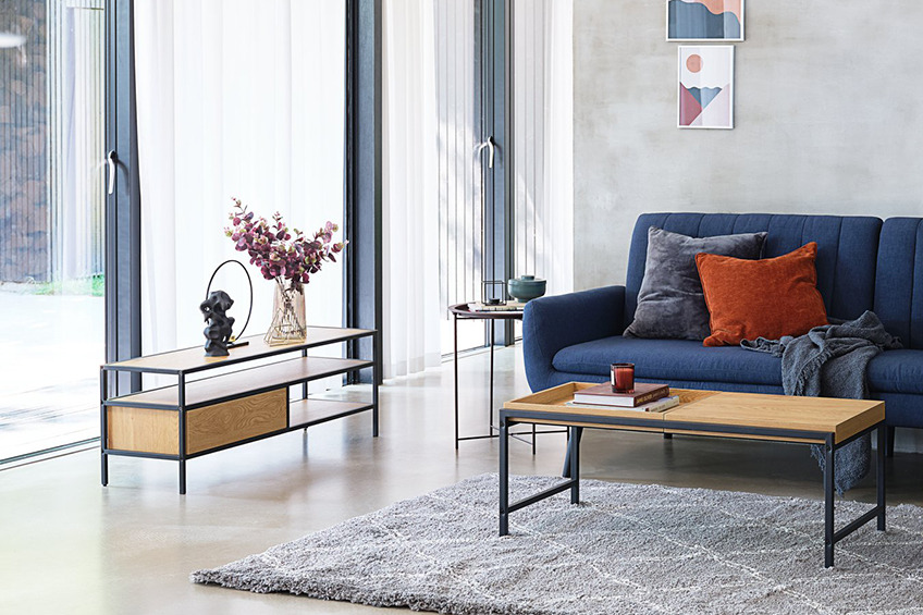 Helles Wohnzimmer mit einem Couchtisch, TV-Bank und einem blauen Sofa