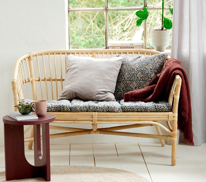 Sofa aus Rattan mit Sitz- und Rückenkissen, burgunderfarbenem Überwurf und einem runden Beistelltisch