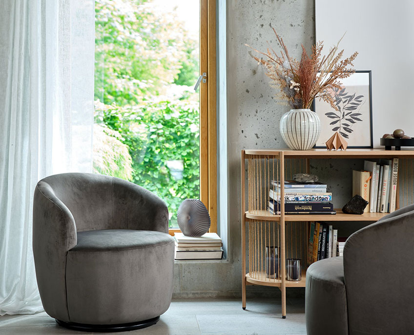 Grauer Sessel und Sideboard mit Büchern und Vase 