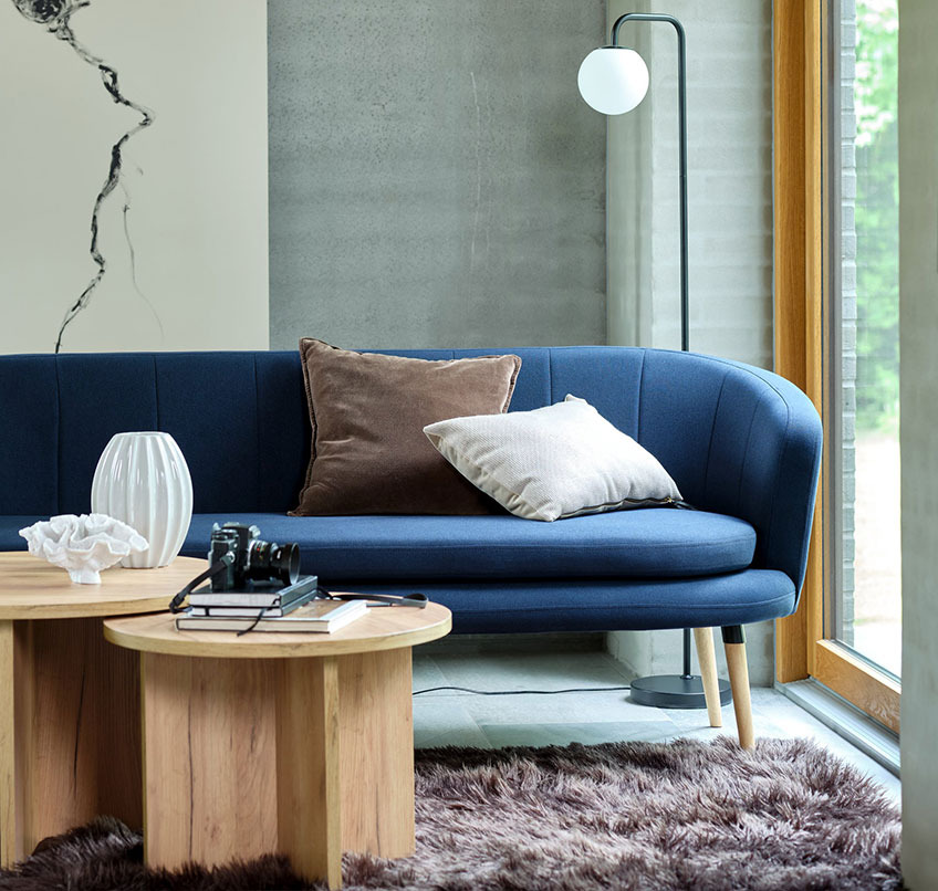 Blaues Sofa, runde Couchtische, brauner Teppich und Stehlampe 