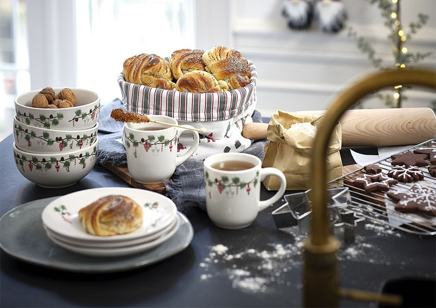 Schalen, Tassen und Teller mit Weihnachtsmotiven und selbstgebackene Süßigkeiten