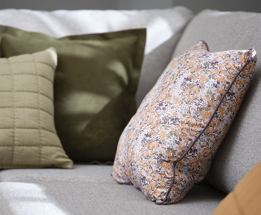 Zierkissen KAMILLE mit Blumenmuster, grünes Zierkissen ALM aus Velours und gestepptes Zierkissen VALMUE Graues Sofa mit grünen und geblümtem Zierkissen