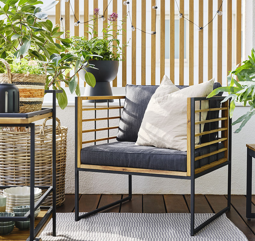 Balkon mit Loungesessel aus Holz und schwarzen und grünen Pflanzen