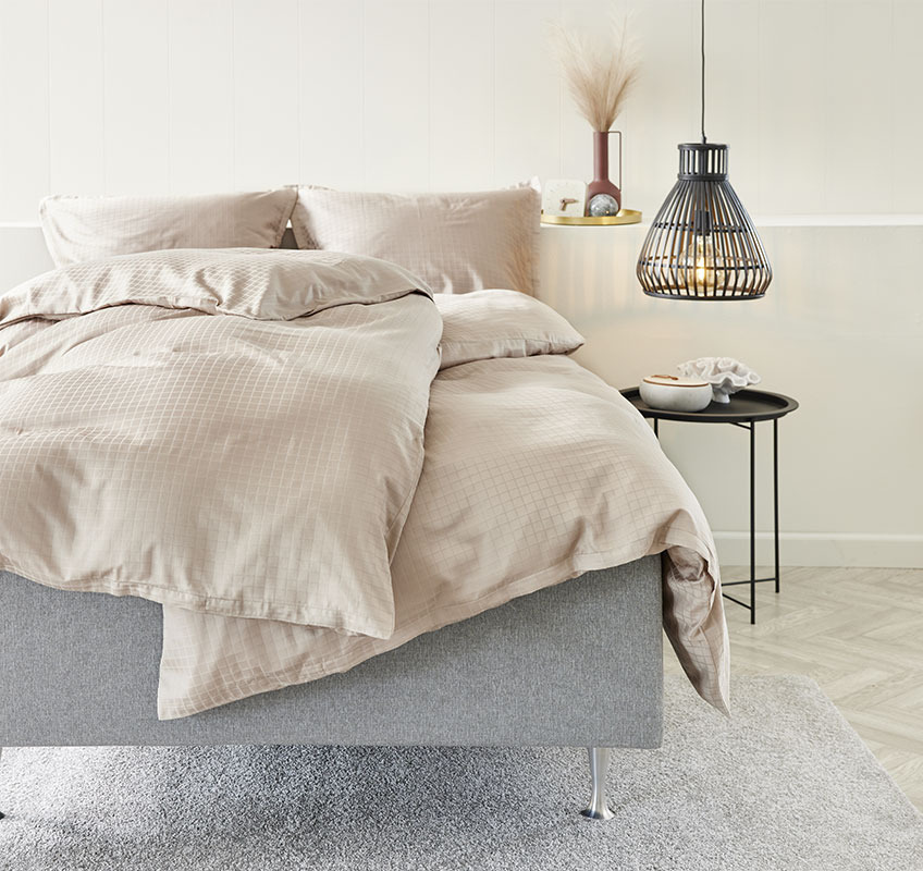 Bett mit sandfarbener Bettwäsche aus hochwertigem Satinstoff 