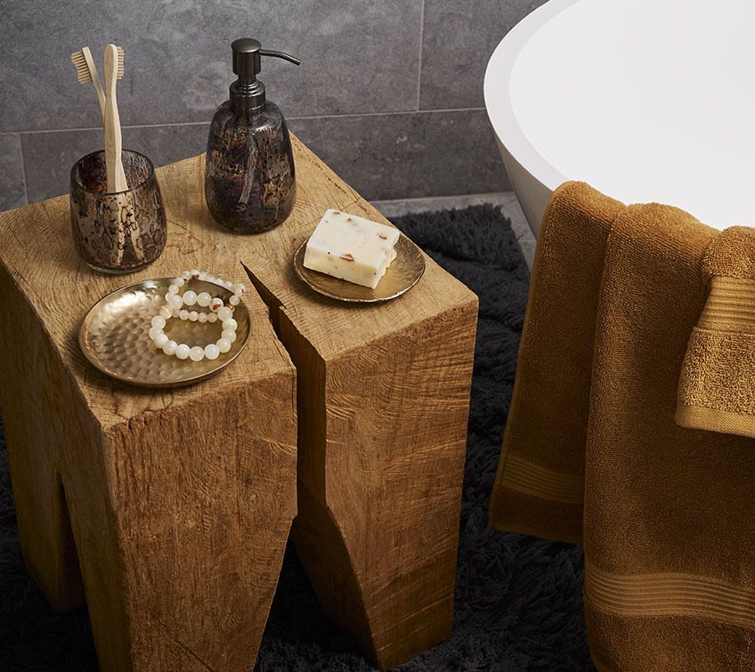 Großer Holzblock mit Deko-Tabletts, Zahnbürstenhalter und Seifenspender in einem Badezimmer