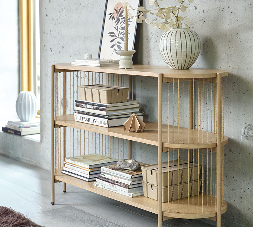 Das EGELEV-Sideboard ist auch in Schwarz erhältlich Wohnzimmer mit einem Sideboard aus heller Eiche mit einer Vase und Büchern sowie Aufbewahrungsboxen