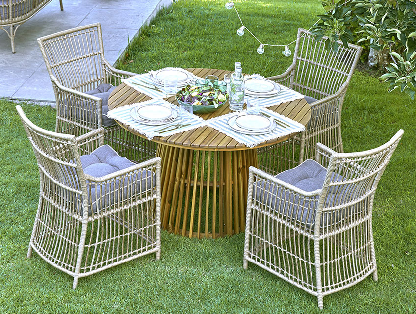 Runder Gartentisch mit mittigem Fuß und vier Gartenstühlen auf einer Wiese