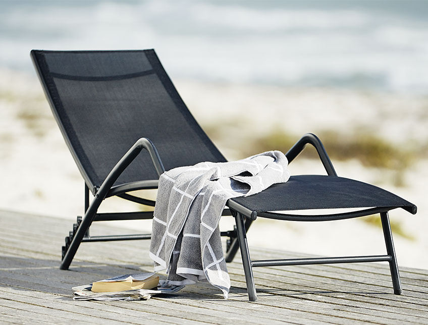 Schwarze Sonnenliege mit Armlehnen auf einer Terrasse am Strand