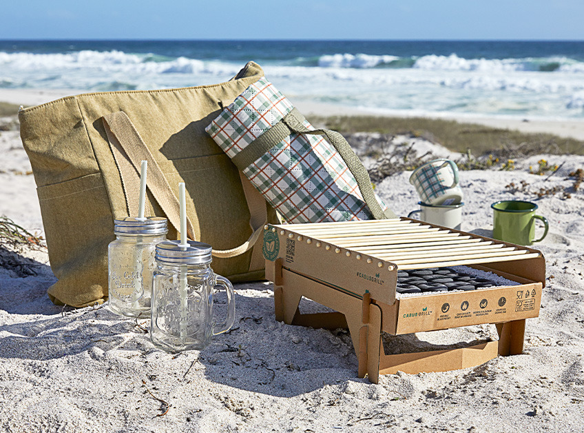 Disposable barbeque, picnic blanket and other picnic accessories on beach