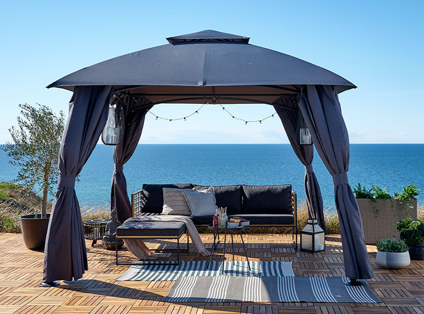 SANKT HANS-Pavillon und UGILT-Lounge-Sofa Grauer Pavillon mit Lounge-Set und Dekoration mit Blick auf das Meer