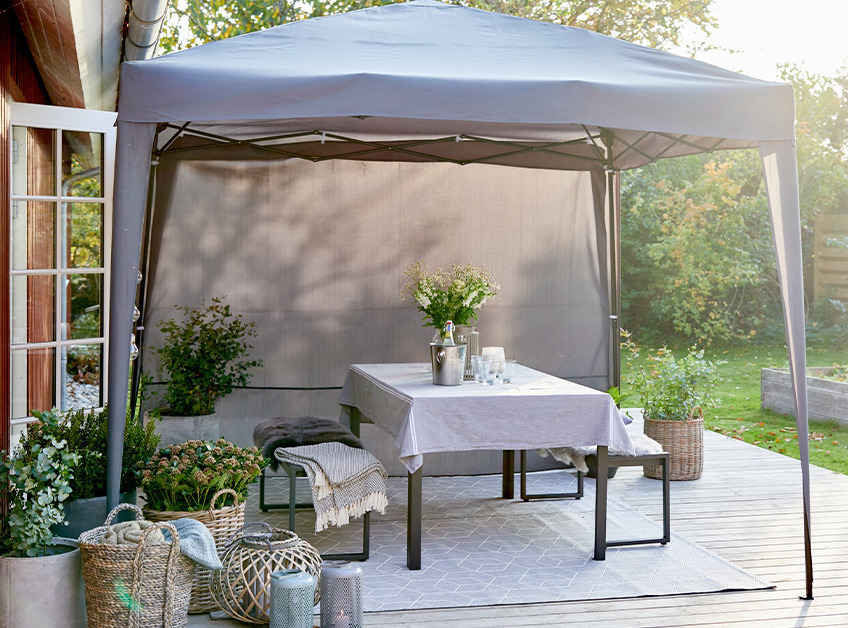 Grauer Pavillon mit einem dekorierten und gedeckten Tisch und Bänken auf der Terrasse