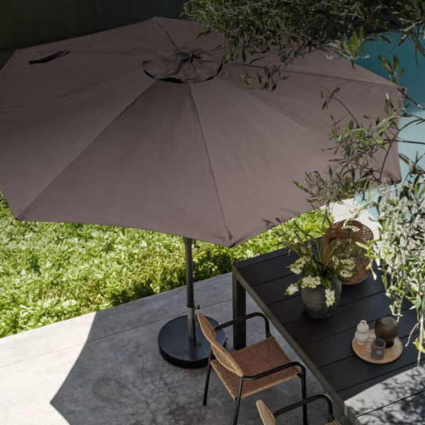 Parasols and shade sails Overhead view of an open taupe cantilever parasol shading an outdoor dining table and woven chairs beside a pool.