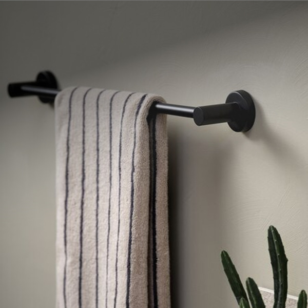 Towel rails Matte black wall-mounted towel bar holding a folded beige towel with navy stripes, beside a potted cactus.