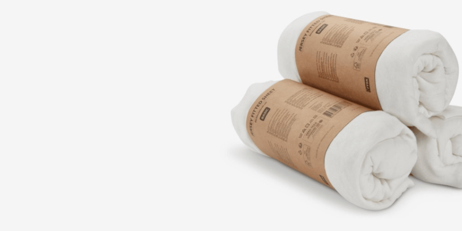 Sheets Two rolled white jersey fitted sheets wrapped in kraft paper packaging bands, shown against a plain light grey background.