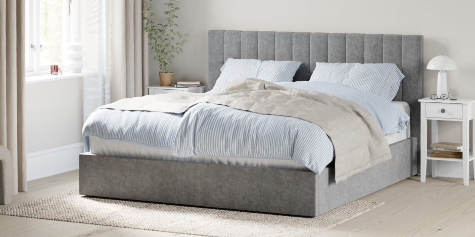 Custom-built beds Light grey channel-tufted upholstered bed with blue and white striped bedding, a beige throw, and a white nightstand with a mushroom lamp and books.